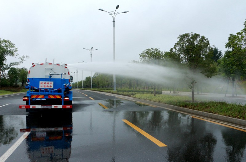 東風灑水車正在噴灑路邊的花草